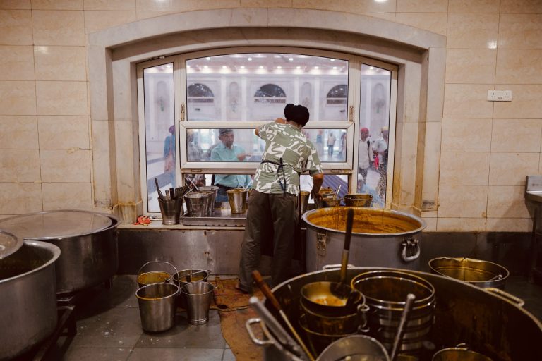 Man at the serving window serving food in the Langar at Gurdwara Bangla Sahib, Delhi, India